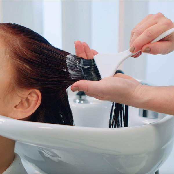 friseur-traegt-haarfarbe-mit-pinsel-auf-nasses-haar-am-waschbecken-im-salon-auf