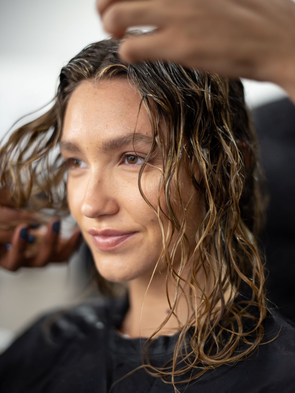 friseur-arbeitet-den-olaplex-no4-curl-bond-shaper-hydrating-curl-conditioner-in-nasses-haar-ein-moodbild