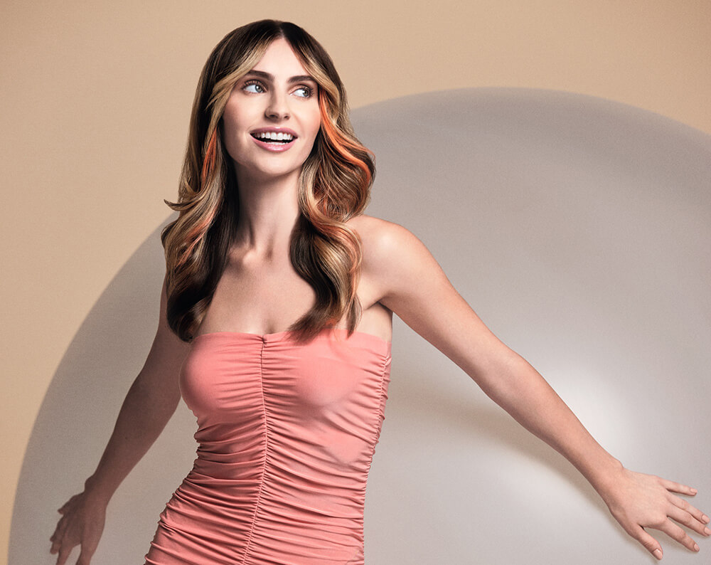 inebrya-imagebild-frau-mit-braun-gefaerbten-haaren-und-blondem-faceframing-in-rosa-kleid-laechelt
